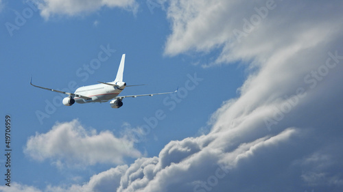 Zoom photo of Airbus A320 passenger airplane flying above clouds in deep blue sky