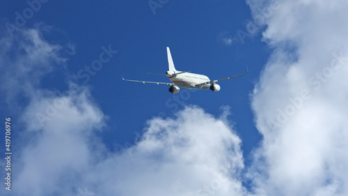 Zoom photo of passenger airplane flying above clouds in deep blue sky
