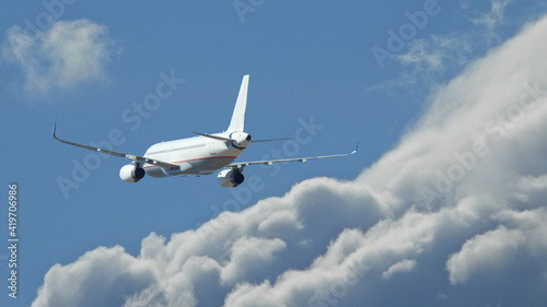 Zoom photo of passenger airplane flying above clouds in deep blue sky © aerial-drone