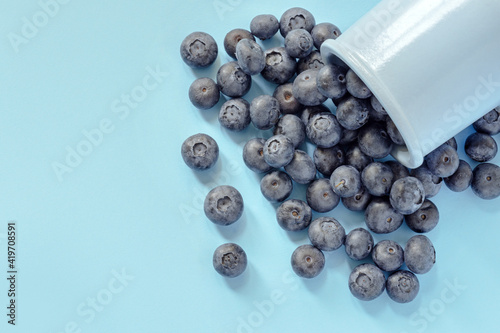 blueberries sprinkled on a blue background, ripe berries heap, mock up for design, top view, layout