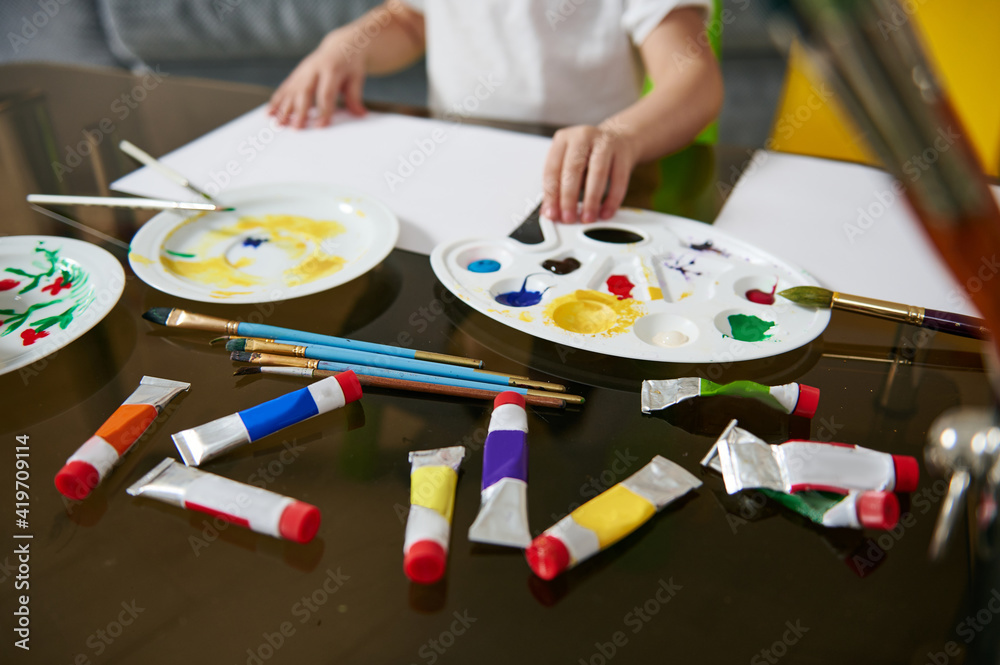 Multi-colored tubes with paints and a palette lying on a glass table. Multi-colored tubes with paints and a palette lying on a glass table.