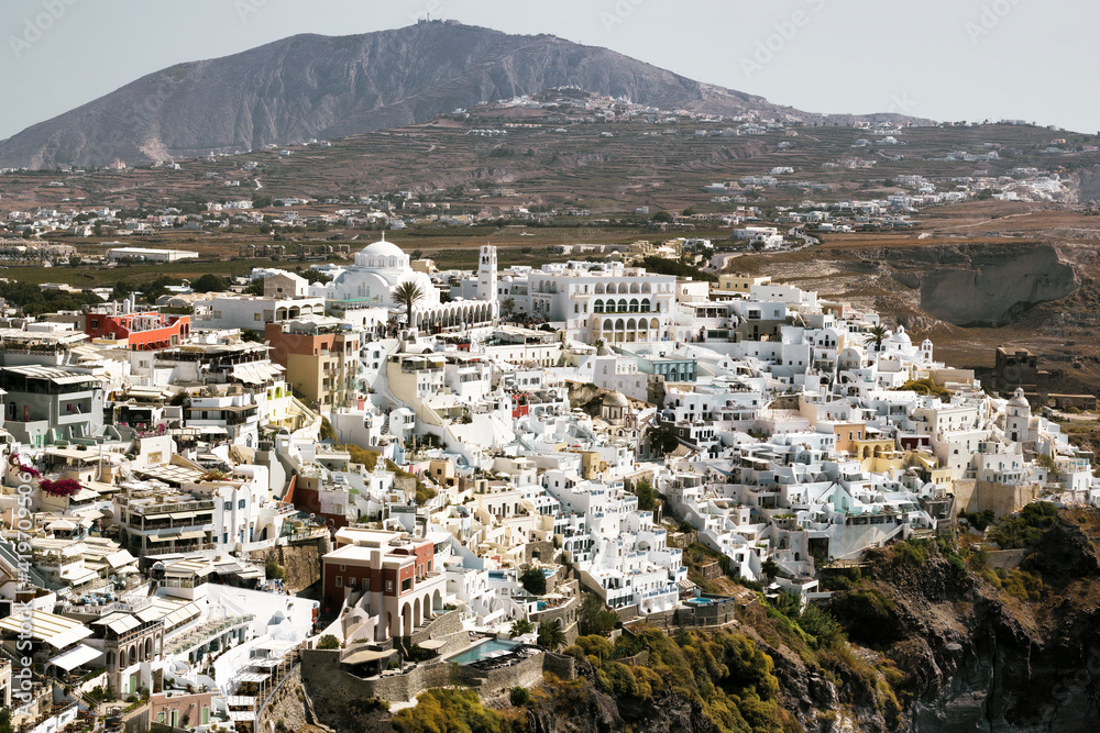 Drone Aerial shot of Thira village in Santorini, Oia located in Greece against mountains. Famous greek island cityscape