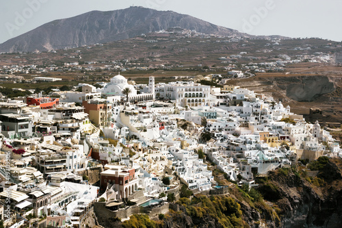Drone Aerial shot of Thira village in Santorini, Oia located in Greece against mountains. Famous greek island cityscape © Arpan