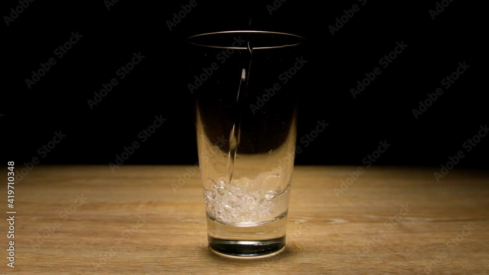 Sparkling water is poured into glass on black background. Close up, 150 fps Sparkling water is poured into glass on black background. Close up, 150 fps