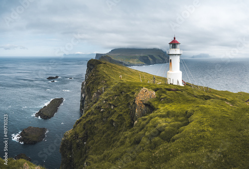 фотография View Towards Lighthouse on the island of Mykines Holmur, Faroe Islandson a cloudy day with view towards Atlantic Ocean