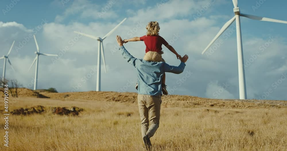 Hopeful father carries son on his back to wind turbines while dreaming of a green renewable energy future, clean and sustainable energy, fighting climate change for future generations