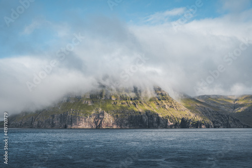 Picturesque green cliffs on Litla Dimun island and atlantic ocean in Faroe islands.