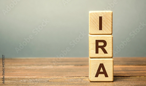 Wooden blocks with the word IRA - individual retirement account. Tax-advantaged account that individuals use to save and invest for retirement. Business and finance concept photo