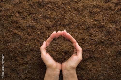 Young adult woman palms holding pile of dark brown dry soil. Care about environment or agriculture. Closeup. Point of view shot. Top down view.