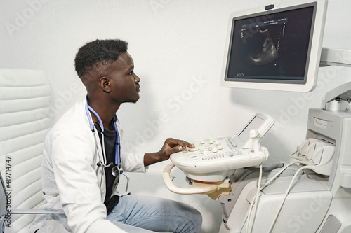 Patient on the couch. Doctor makes an ultrasound diagnosis. Man in a white uniform.