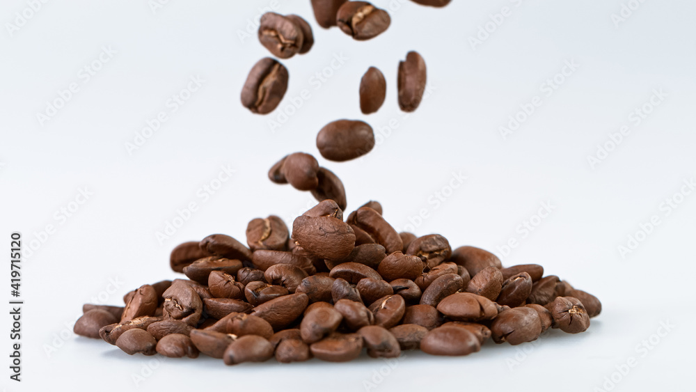 Obraz premium Falling Roasted Coffee Beans on White Background, close-up.