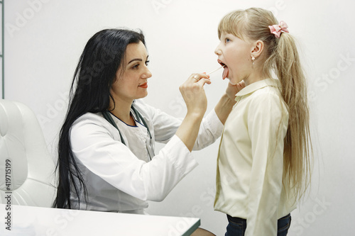 Girl with long hair. Doctor looks in ear. Hospital ward.