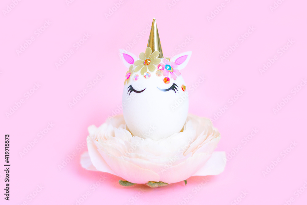 white Easter eggs decorated in the form of unicorns on ranunculus flower on pink background, a minimal creative concept of a happy Easter white Easter eggs decorated in the form of unicorns on ranunculus flower on pink background, a minimal creative concept of a happy Easter