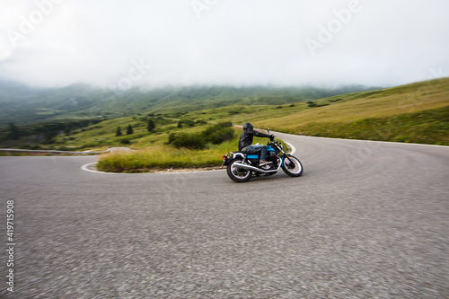 Motorcycle driver riding on mountain highway  Dolomites  central Europe.
