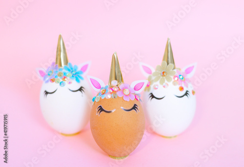 brown and white Easter eggs decorated in the form of unicorns on a pink background, a minimal creative concept of a happy Easter