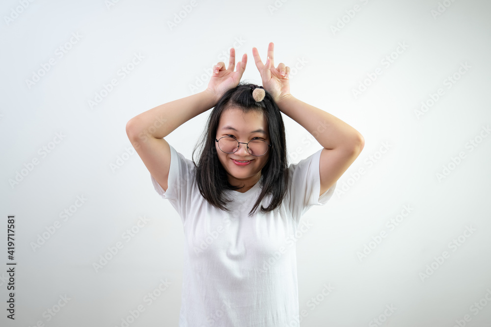 Asian glasses young woman is raising up victory sign by two fingers like the rabbit ears on white background. Asian glasses young woman is raising up victory sign by two fingers like the rabbit ears on white background.