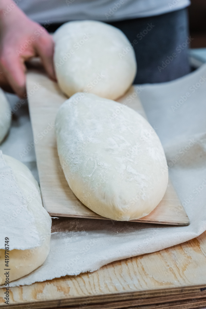 Baker making bread , man hands , kneading a dough , cooking coat.The concept of small bakeries, craft traditional bread Baker making bread , man hands , kneading a dough , cooking coat.The concept of small bakeries, craft traditional bread