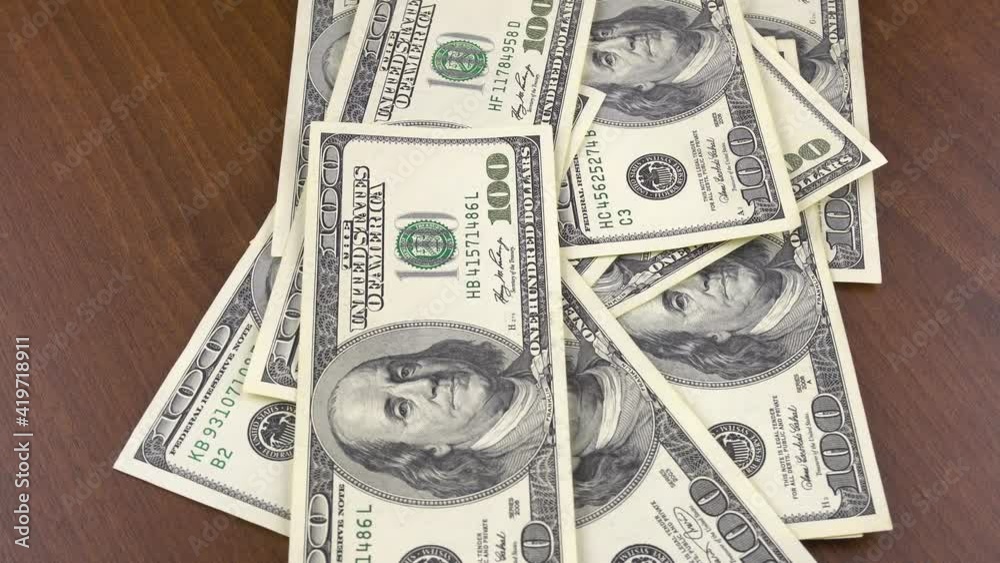 One hundred dollar bills fall on the rotating table.Financial background.Close-up shot of one hundred dollar bills