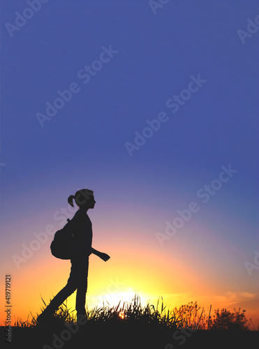 People  teens  hiking and travel concept. Silhouette of a young girl on a mountain top.Young girl with backpack enjoying sunset.Tourist traveler at sunset.