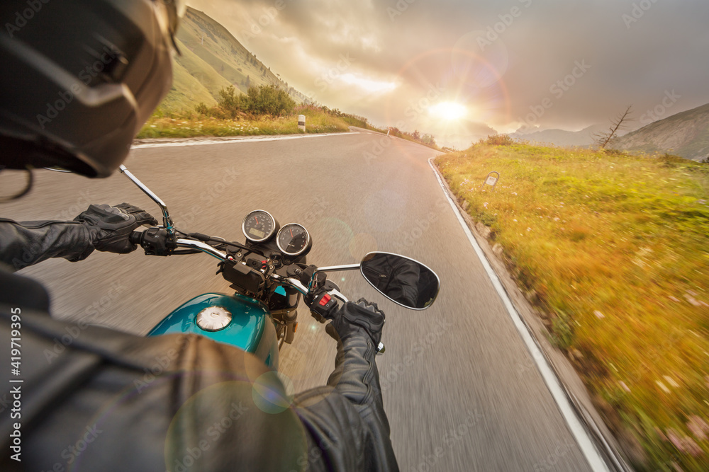 Fototapeta premium Motorcycle driver riding on mountain highway, handlebars view, Dolomites, central Europe.