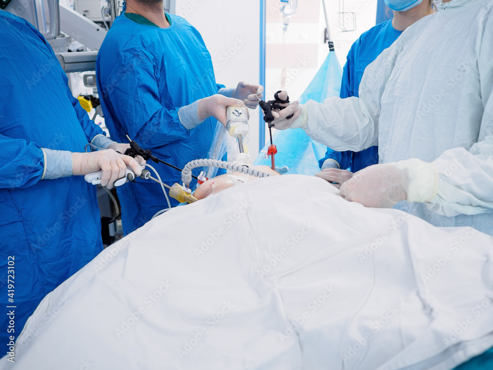 Surgeons in blue uniforms perform laparoscopic surgery using special