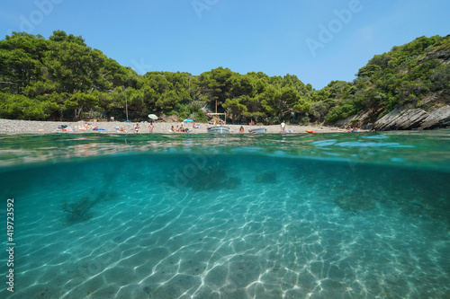 Mediterranean sea vacations in Spain, tranquil cove with tourists on the beach, split view over and under water surface, Costa Brava, Cala Guillola, Cadaques, Cap de Creus, Catalonia