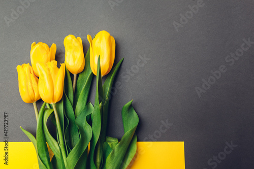 Mother's day flowers. Bouquet of yellow tulips on grey background. Present, gift for spring holiday. Space photo