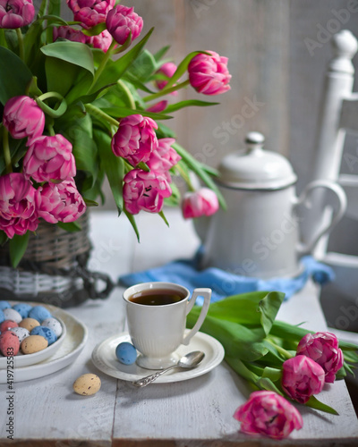 colorful eggs and rose tulips, cup of tea over white wood table