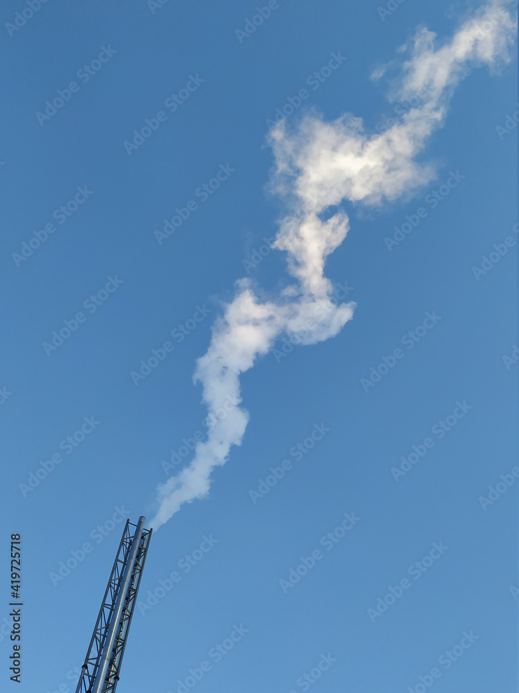 Emissions in the form of white smoke into the atmosphere from a metal pipe of a stationary block-modular boiler house against a blue sky. Environment, atmosphere. Global warming. Emissions in the form of white smoke into the atmosphere from a metal pipe of a stationary block-modular boiler house against a blue sky. Environment, atmosphere. Global warming.