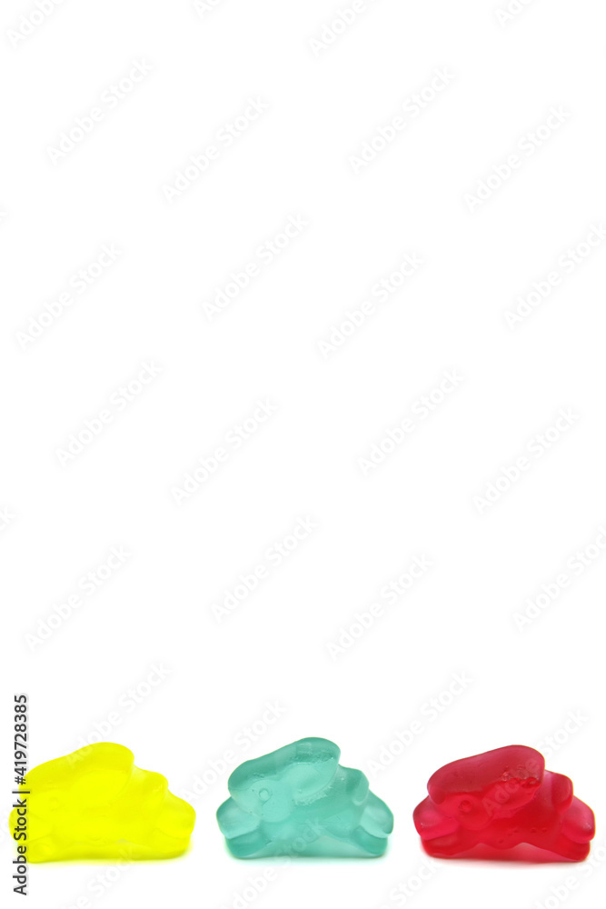 Obraz premium Colourful gummy bunnies candies isolated on white background. Fun candy macro shot. Copy space for your text.