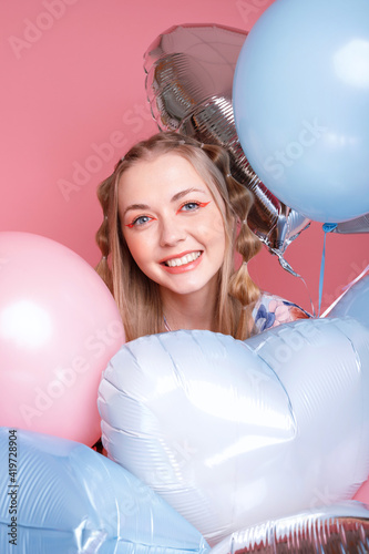 Woman happy with balloons on a pink background
