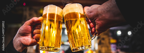 Картината върху платно Close-up view of a two glass of beer in hand