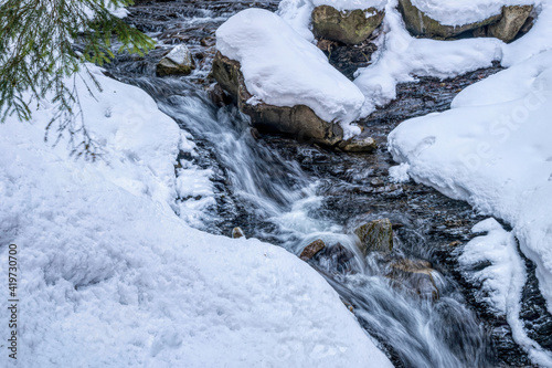 Waterfall, river with rapids and cold winter mountain landscape