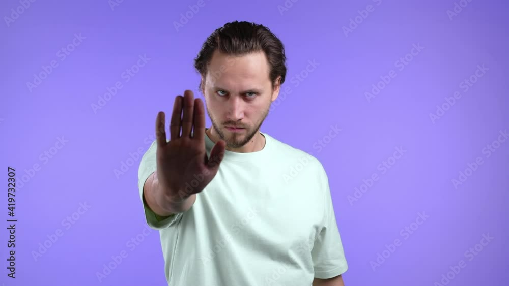 Portrait of serious man disapproving with no hand sign make basta, negation, enough gesture. Denying, Rejecting, Disagree. Portrait of handsome guy on violet background Portrait of serious man disapproving with no hand sign make basta, negation, enough gesture. Denying, Rejecting, Disagree. Portrait of handsome guy on violet background