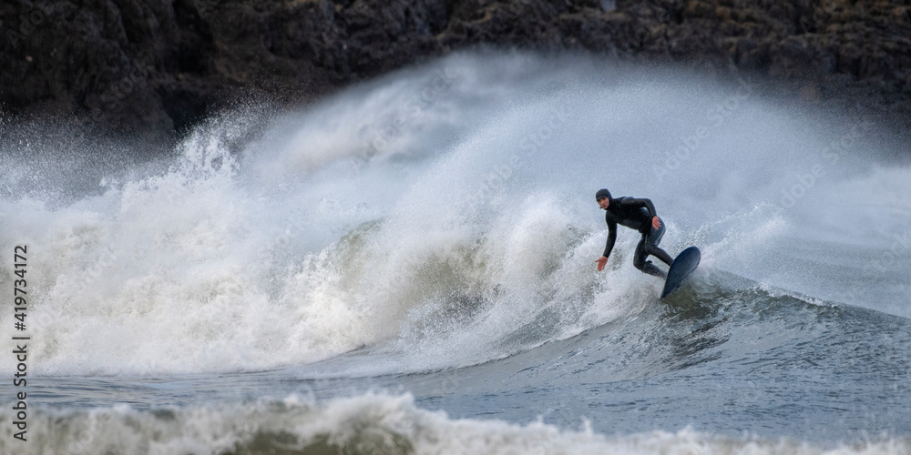 Mature man surfing on waves splashing in sea, Broad Haven South Beach, Wales, UK