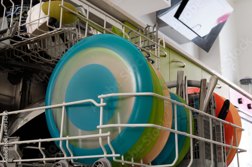 Dishwashing full of silverware and colored plates.