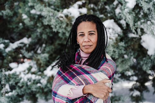 Mature woman with arms crossed wrapped in plaid shawl at park photo