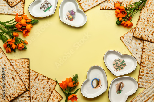Pesach celebration concept (jewish Passover holiday).Matzo, special heart shaped plates for seder pesach (with the inscriptions: egg, shankbone, bitterness, parsley, charoset) and flowers.