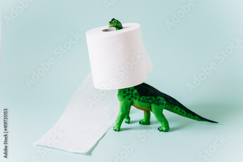 Diplodocus dinosaur toy with a roll of toilet paper around the neck on mint green background