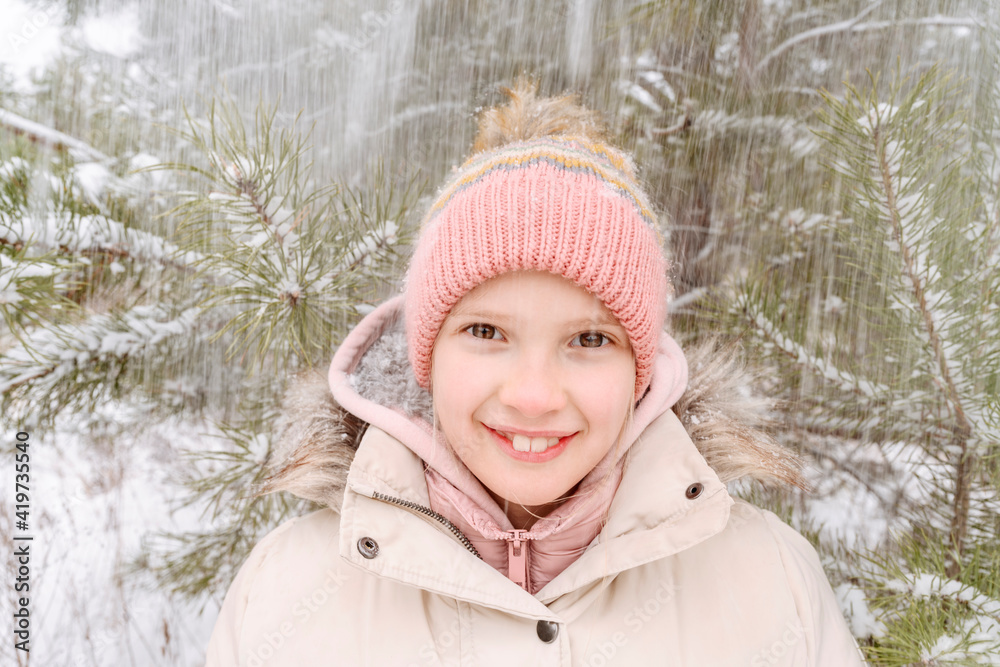 Close-up portrait of smiling girl enjoying snowfall in forest Close-up portrait of smiling girl enjoying snowfall in forest