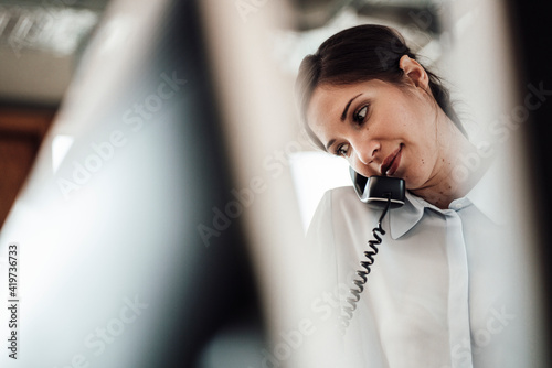 Female entrepreneur talking on landline phone at office photo
