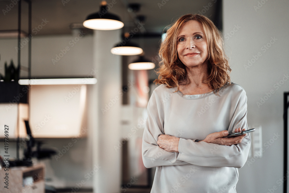 Confident businesswoman with arms crossed standing in office Confident businesswoman with arms crossed standing in office