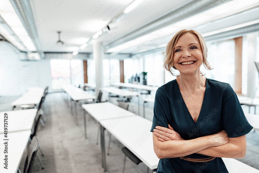 Female entrepreneur with arms crossed looking away in board room at office Female entrepreneur with arms crossed looking away in board room at office
