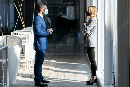 Business people wearing protective face mask standing at social distance while working in office during COVID-19