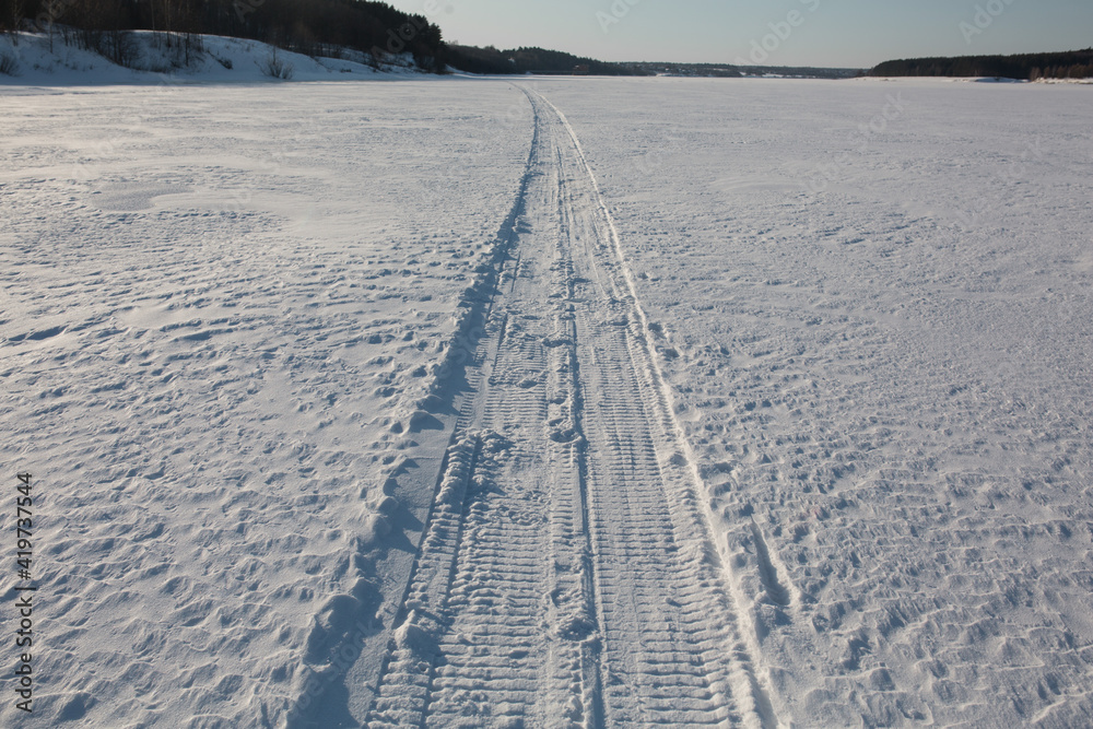 Obraz premium The trail from the snowmobile goes into the distance.