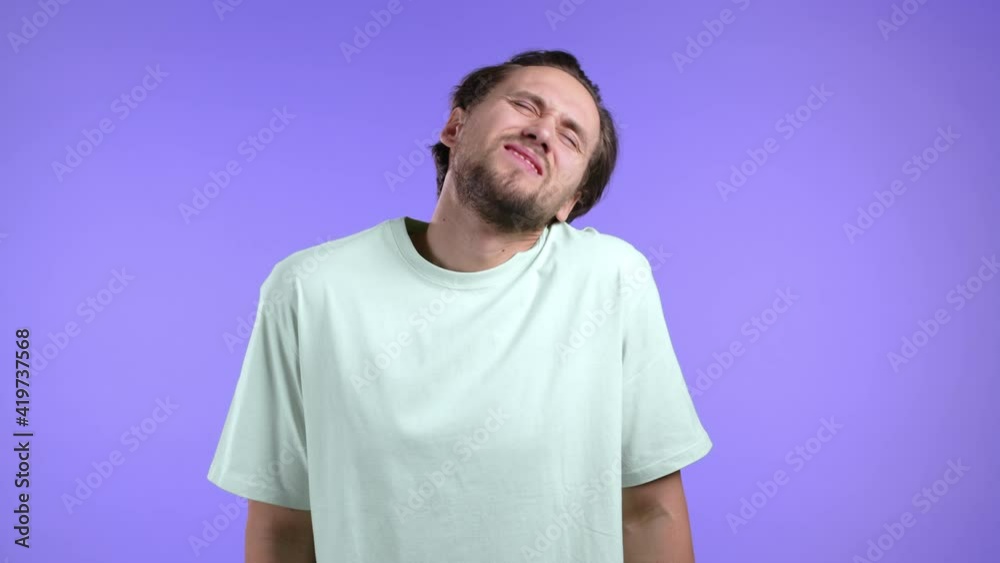 Tired young man having pain - neck ache. Guy in casual t-shirt takes break and kneads sore neck muscles Tired young man having pain - neck ache. Guy in casual t-shirt takes break and kneads sore neck muscles