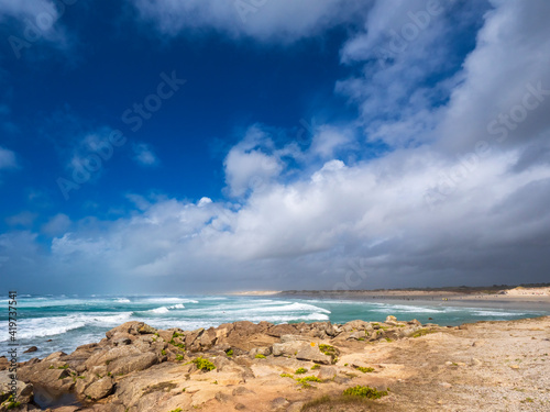 Landscape by sea against cloudy sky