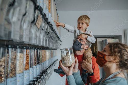 Father and son shopping in retail store while standing by female owner during pandemic photo