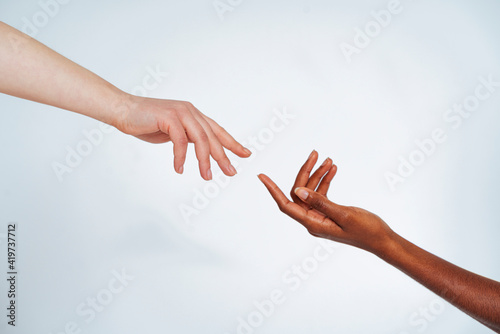Friends stretching hands toward each other against white background photo