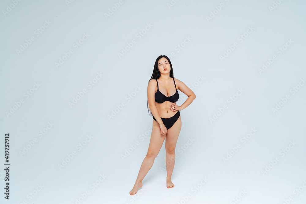 Oversized young woman wearing black bikini posing against white background Oversized young woman wearing black bikini posing against white background